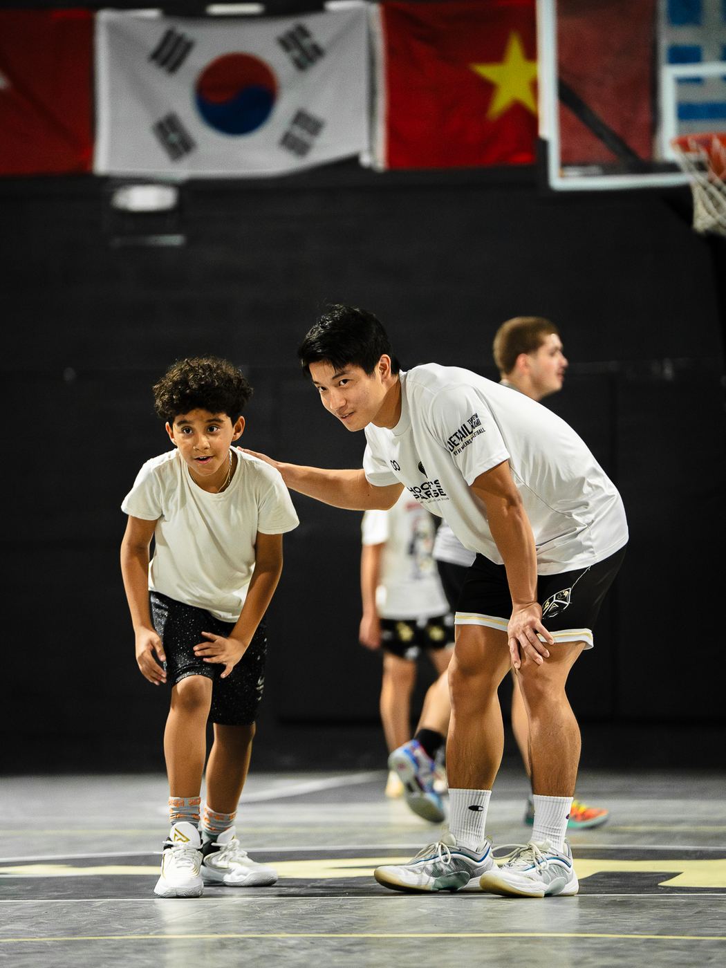 DETAIL Miami coach crouching beside a young player with a hand on the player's shoulder, both in a ready stance