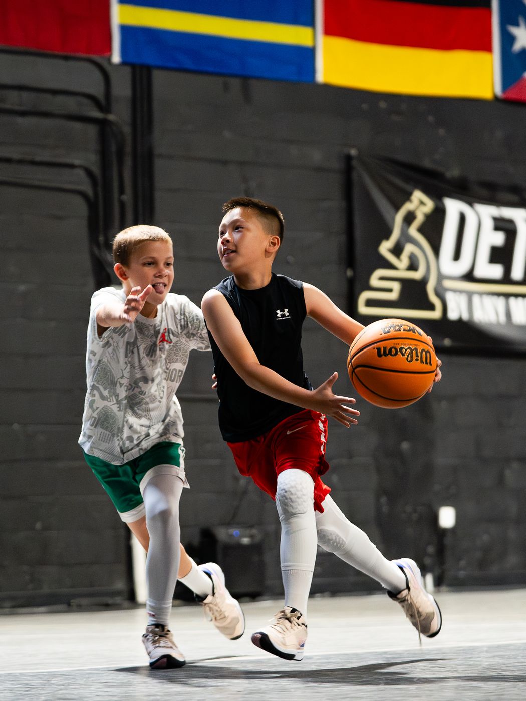 Youth player driving to the basket with the ball while another athlete defends during live play at DETAIL Miami